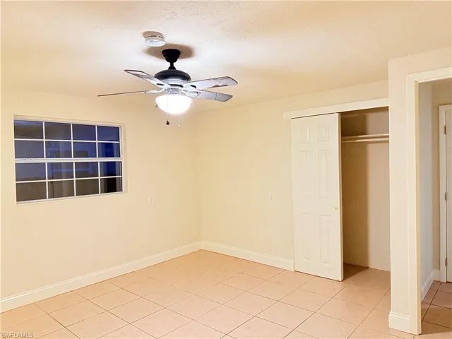 Unfurnished bedroom with light tile patterned floors, a closet, and a ceiling fan