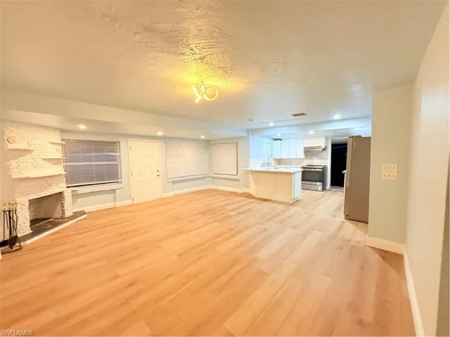 Unfurnished living room with light wood finished floors, a stone fireplace, recessed lighting, and a textured ceiling