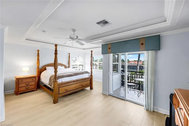 Bedroom with a raised ceiling, crown molding, light wood finished floors, access to outside, and ceiling fan