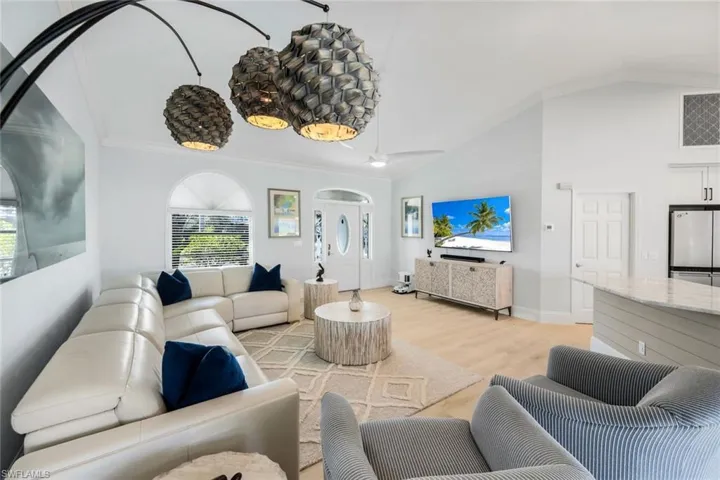 Living area featuring vaulted ceiling, crown molding, and light wood-style floors