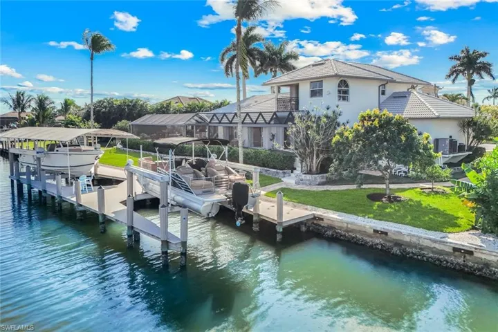 Dock featuring boat lift, a water view, and a yard