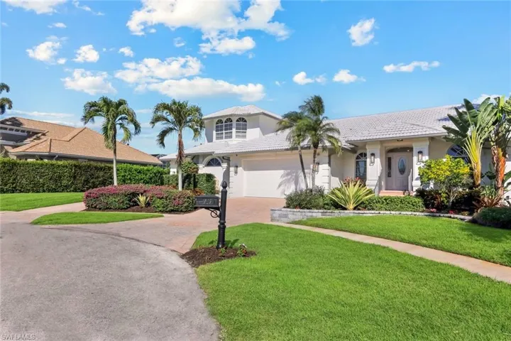 View of front of property featuring a front yard, driveway, a tiled roof, and stucco siding