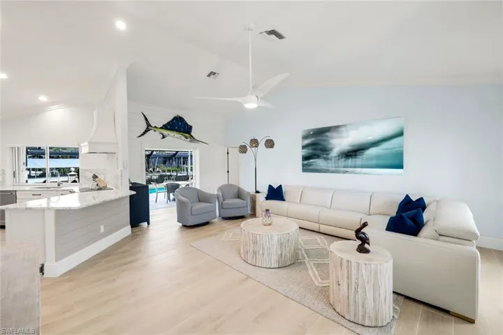 Living room with lofted ceiling, light wood-type flooring, crown molding, and ceiling fan