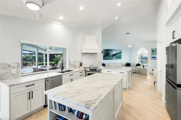 Kitchen with open shelves, lofted ceiling, white cabinets, appliances with stainless steel finishes, and light stone countertops