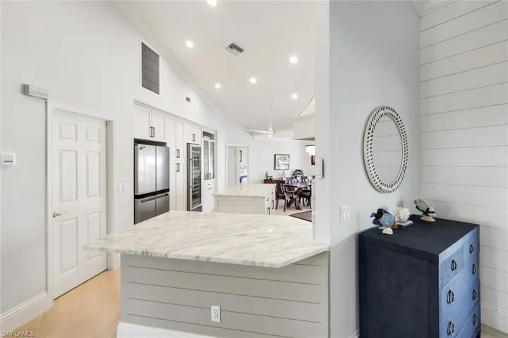 Kitchen featuring white cabinets, light stone counters, a center island, recessed lighting, and crown molding