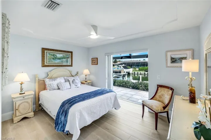 Bedroom featuring access to outside, wood finished floors, a ceiling fan, and a water view