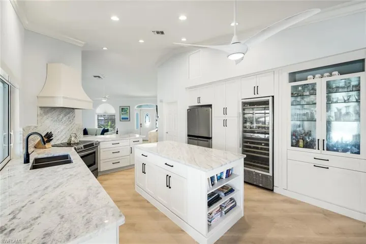 Kitchen with ceiling fan, open shelves, hanging light fixtures, ornamental molding, and premium range hood