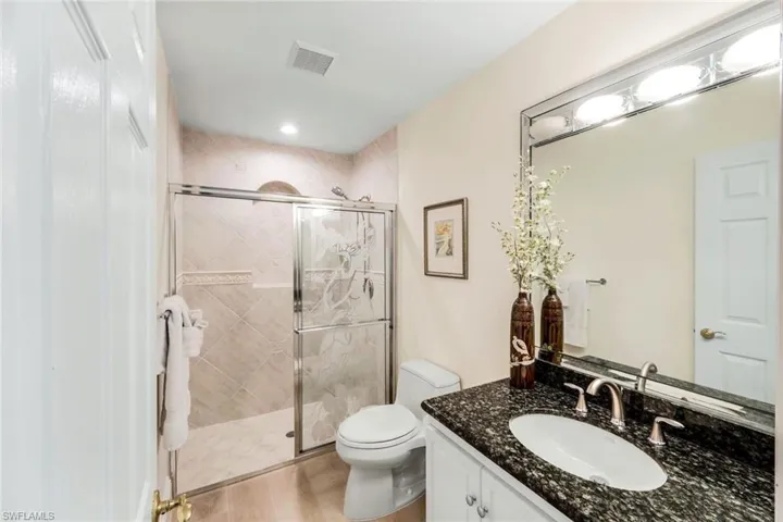 Bathroom with vanity, a stall shower, and light wood-type flooring