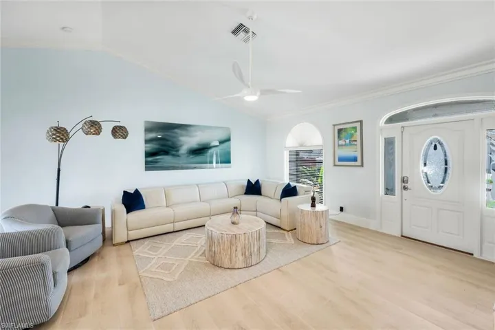 Living area with vaulted ceiling, crown molding, wood finished floors, and ceiling fan