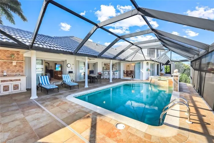 View of swimming pool featuring a patio area, a sunroom, a pool with connected hot tub, and glass enclosure