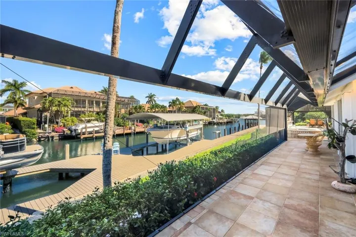 View of patio featuring a dock, boat lift, a sunroom, and a water view