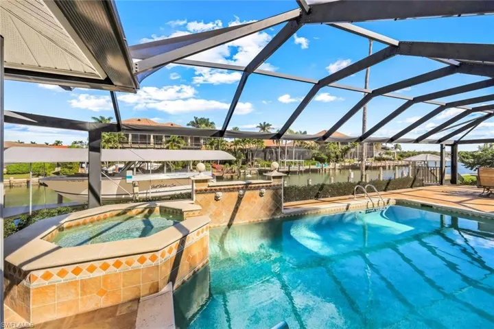 View of pool with a lanai, a water view, a boat dock, and boat lift
