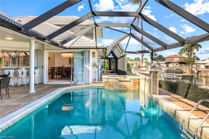 View of swimming pool with glass enclosure, a patio area, a sunroom, and a pool with connected hot tub
