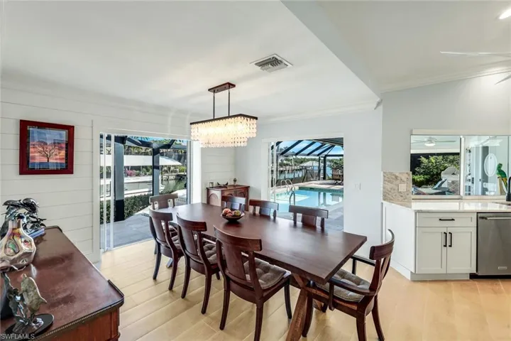 Dining area with a sunroom, light wood-style floors, and ornamental molding