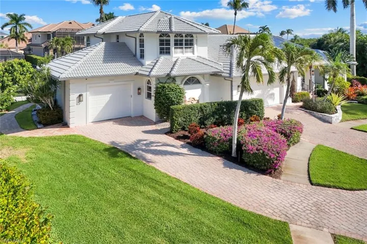 View of front facade featuring stucco siding, decorative driveway, a front yard, and a tile roof