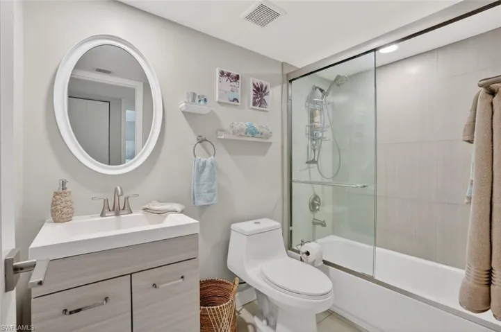 Full bath with vanity and tiled bath / shower combo with glass door