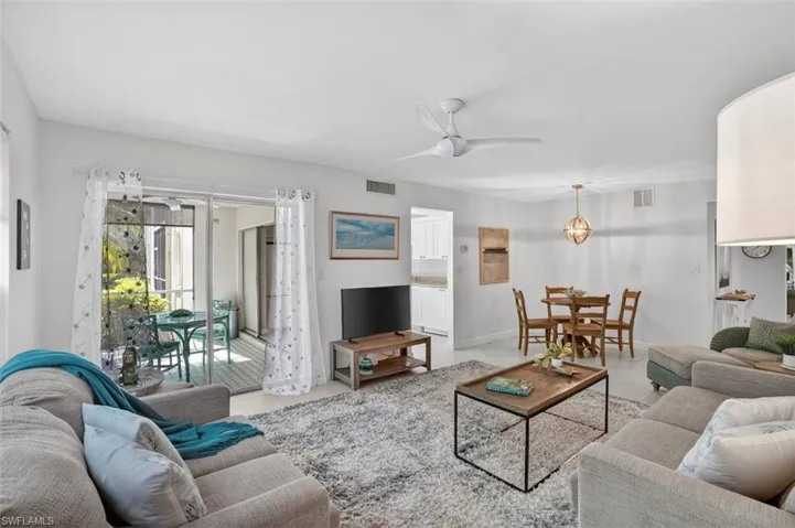 Tiled living room with ceiling fan and sliders to the lanai