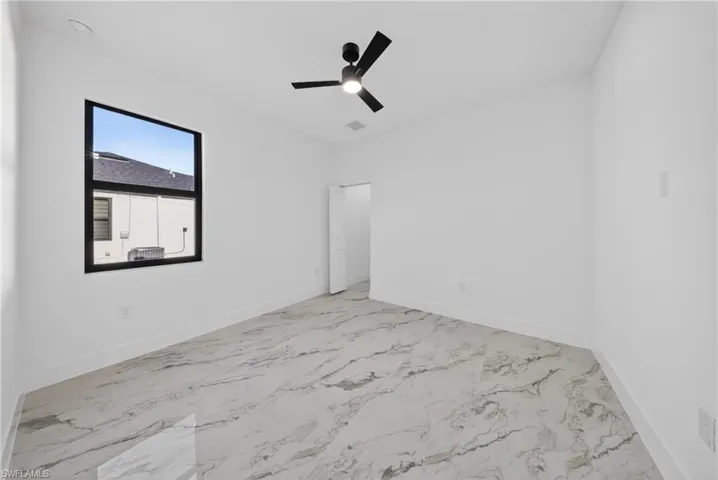Unfurnished room with ceiling fan and light marble finish floors