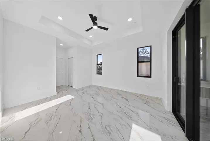 Spare room with recessed lighting, ceiling fan, light marble finish flooring, and a tray ceiling