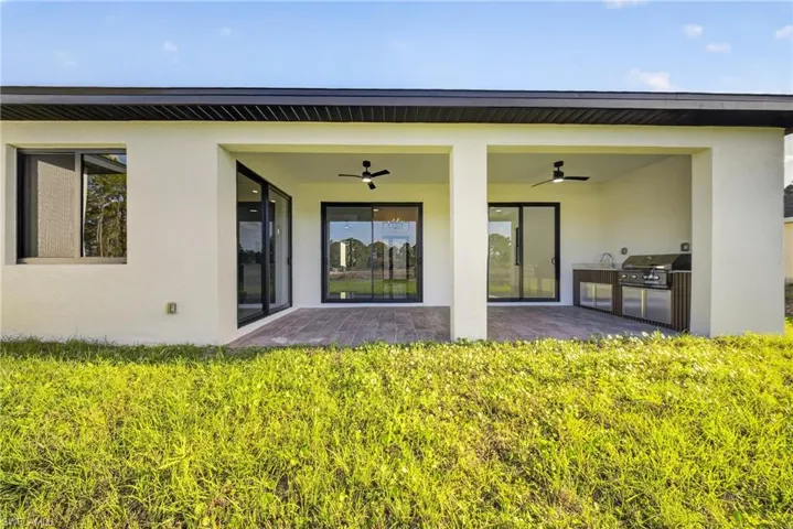 Back of property featuring stucco siding, a ceiling fan, a patio, and an outdoor kitchen
