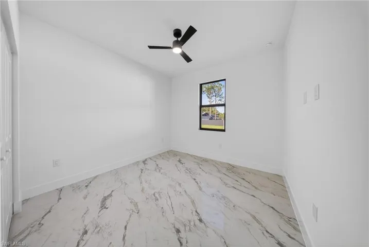 Spare room with a ceiling fan, lofted ceiling, and light marble finish flooring