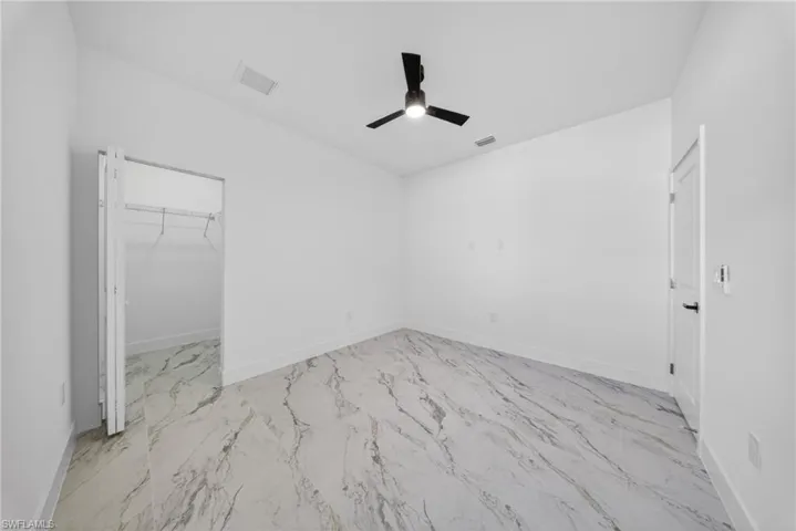 Unfurnished bedroom featuring a walk in closet and a ceiling fan