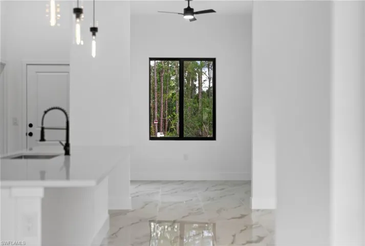 Kitchen with ceiling fan, pendant lighting, light marble finish flooring, and a center island with sink