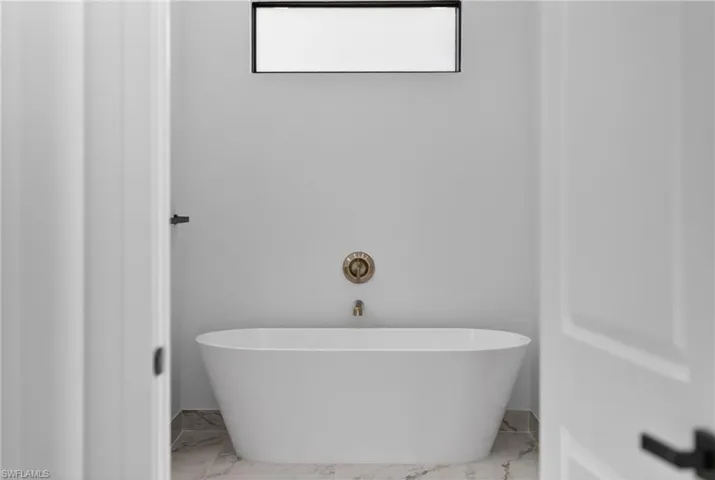 Full bathroom with a freestanding tub and light marble finish floors
