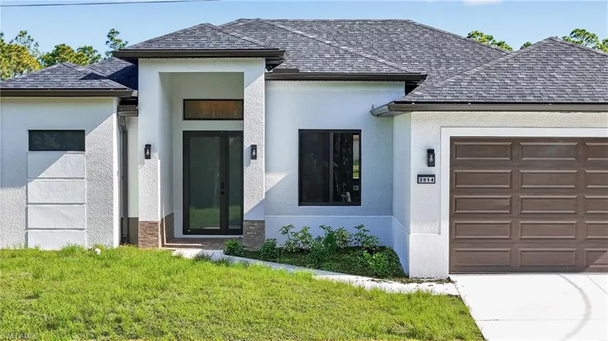 View of front of home featuring an attached garage, stucco siding, and a front lawn