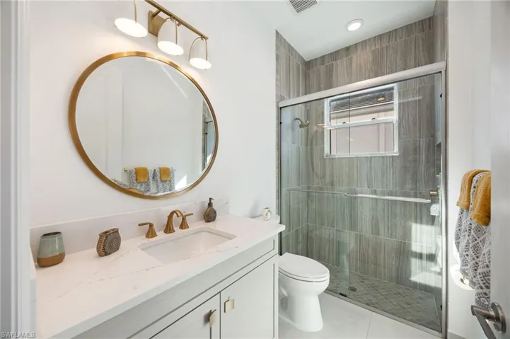 Bathroom 2 is located within the generous bedroom 2 suite, with gold accents and a light color scheme.