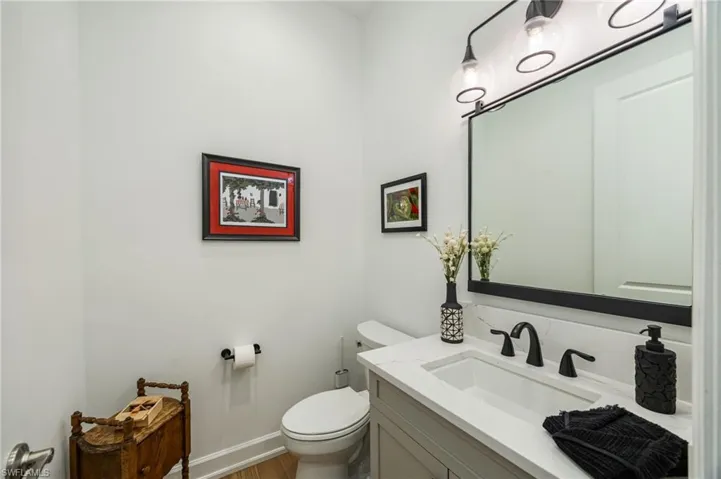 The powder bathroom is light and bright, with wood flooring and matte black plumbing.