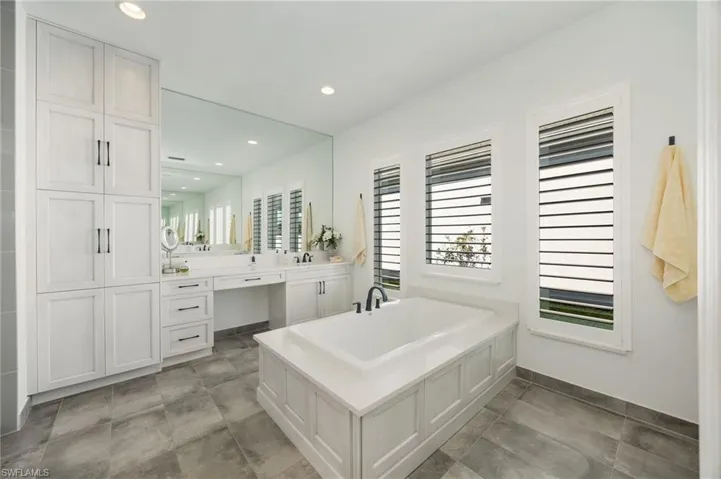 The primary bathroom with large soaking tub, upgraded shower with frameless glass enclsoure, linen tower, and so much natural light!