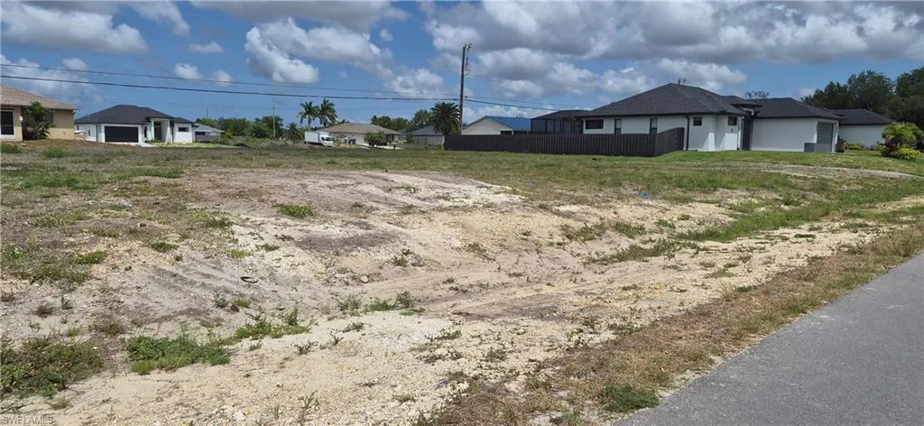 Expansive land parcel featuring existing surrounding residential properties and partial asphalt paving