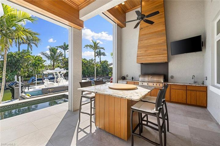 Outdoor kitchen with Blaze Grille, hood, refrigerator and sink. Also can be fully enclosed with remote screens.