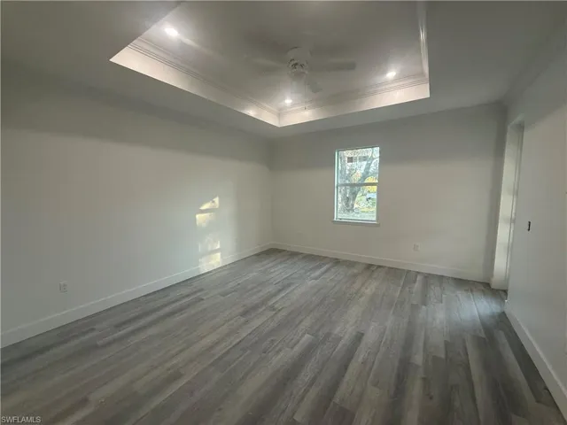 Spare room with ornamental molding, dark hardwood / wood-style floors, and a raised ceiling