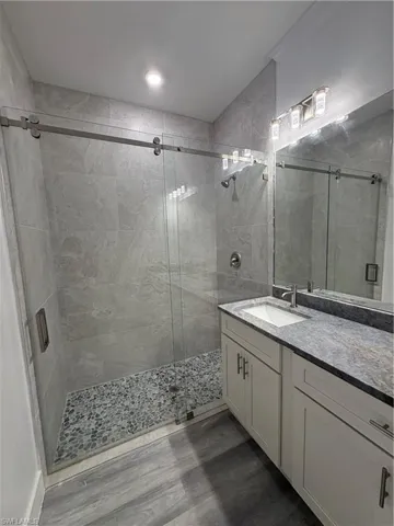 Bathroom featuring vanity, walk in shower, and wood-type flooring
