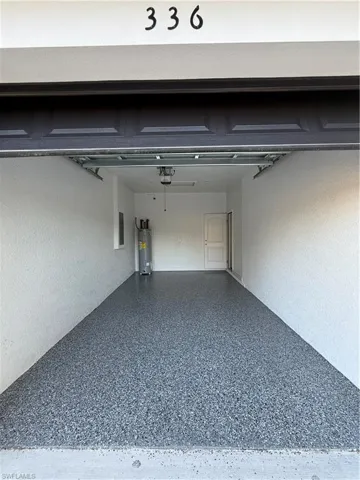 Garage with water heater, electric panel, and a garage door opener