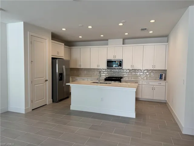 Kitchen layout with quartz countertops, soft-close cabinetry and stainless steel appliances