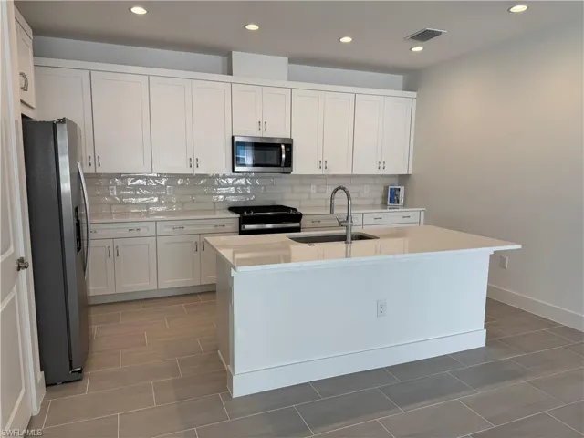 Kitchen layout with quartz countertops, soft-close cabinetry and stainless steel appliances