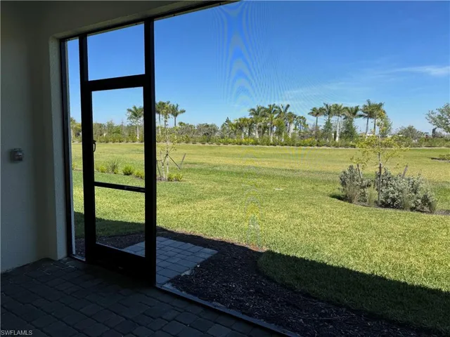 Backyard covered lanai with screen enclosure and view of landscaped area