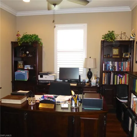 Office space with ornamental molding, ceiling fan, and dark hardwood / wood-style floors