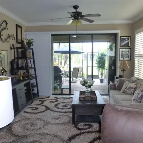 Living room with crown molding, ceiling fan, and a wealth of natural light