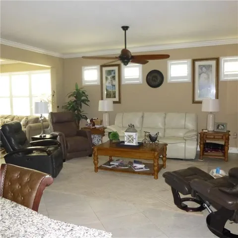 Tiled living room with ornamental molding and ceiling fan