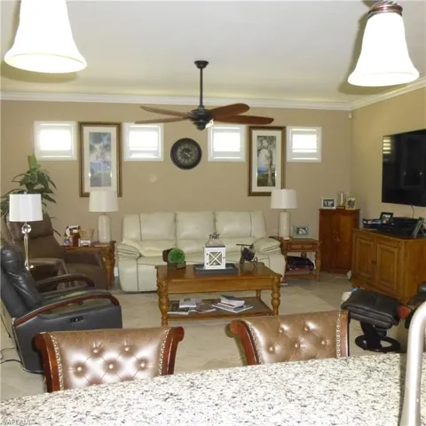 Living room featuring a healthy amount of sunlight, ornamental molding, and ceiling fan