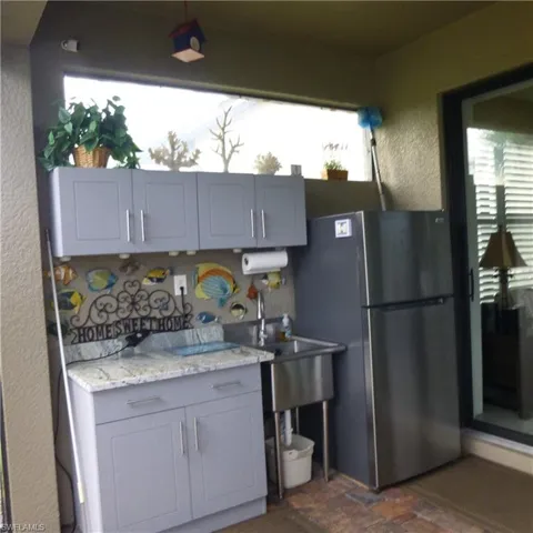 Kitchen featuring light stone countertops, stainless steel refrigerator, and gray cabinetry