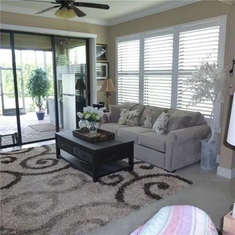 Living room featuring ornamental molding, tile patterned floors, and ceiling fan