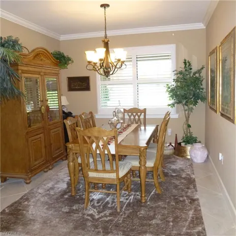 Tiled dining room with a chandelier, french doors, and crown molding