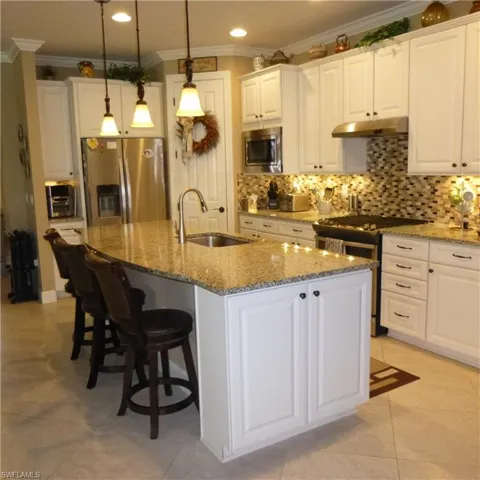 Kitchen with sink, stainless steel appliances, a center island with sink, and white cabinetry