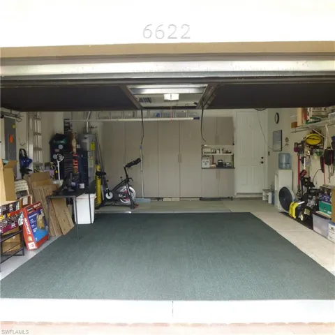 Garage featuring a workshop area, electric panel, and gas water heater