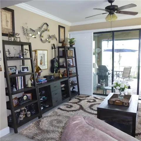 Living area featuring carpet flooring, crown molding, and ceiling fan